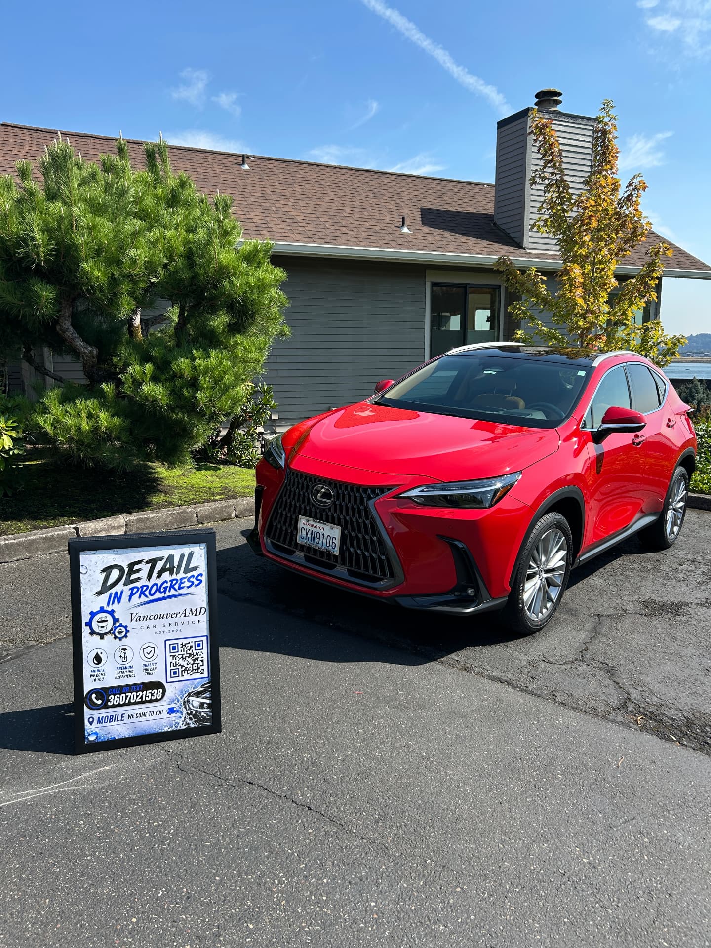 Red Lexus NX parked at a customer's home beside Vancouver AMD's work-in-progress sign
